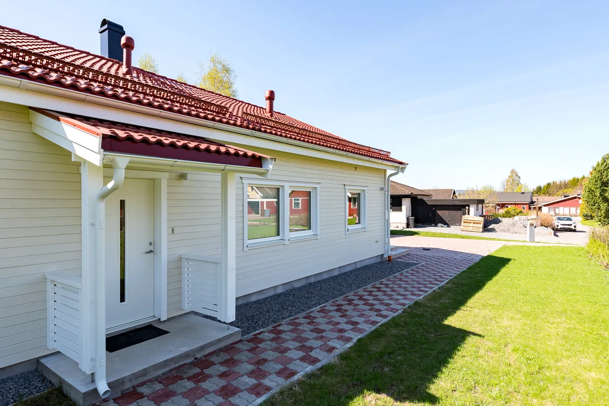 Vit fasad och rött pannat tak på en villa