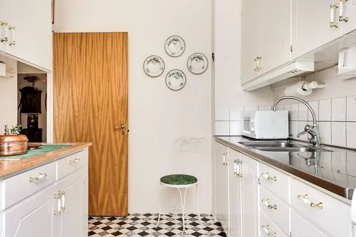 Kök med vita luckor och mönstrat klinkergolv
