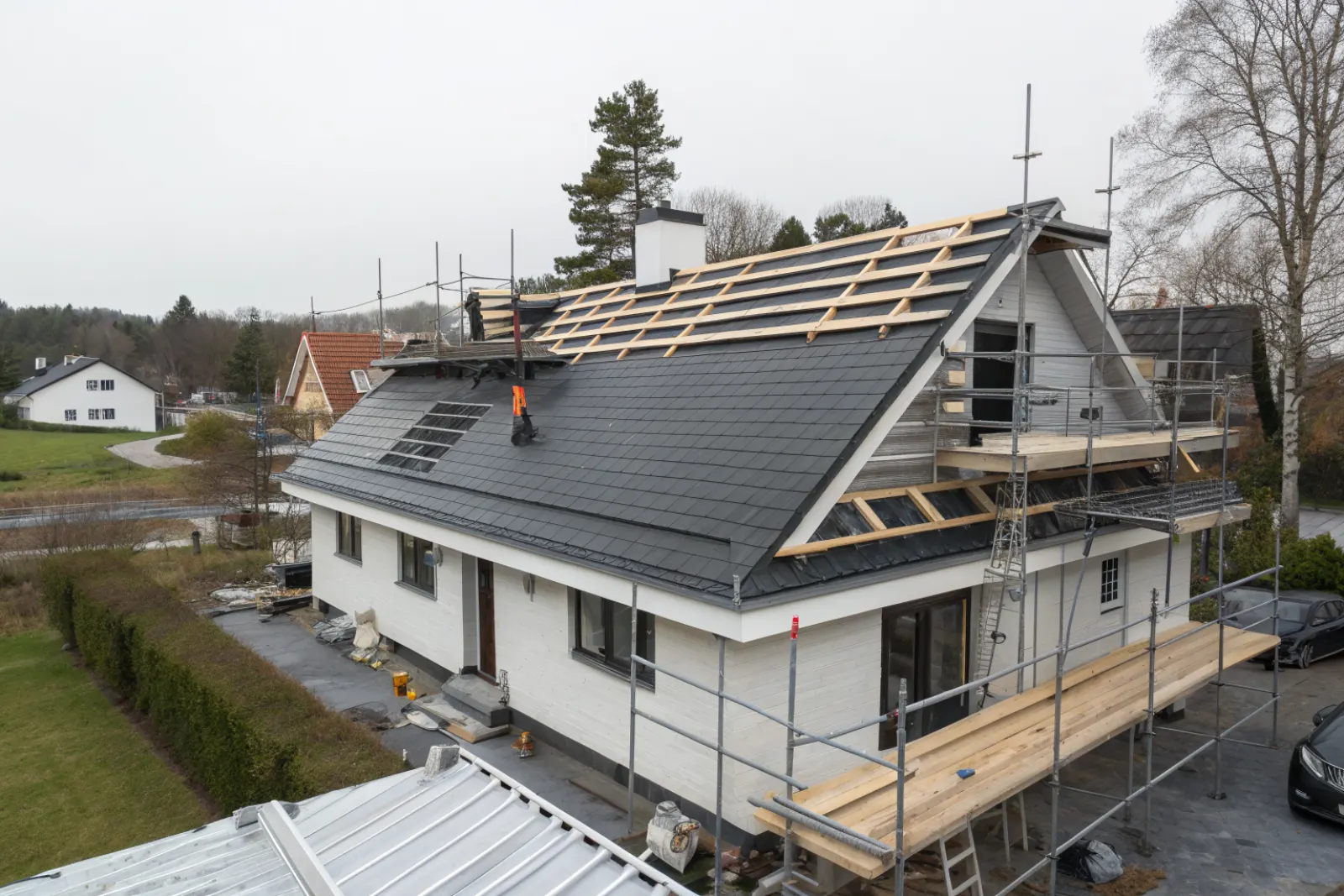 Nytt tak läggs på en villa – ny underlagspapp och läkt överst, nya betongpannor nederst