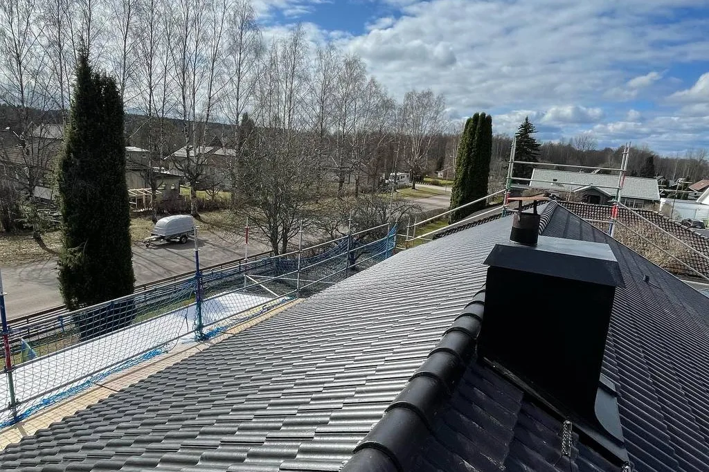 Svart betongpannetak vid skorstenen efter renovering